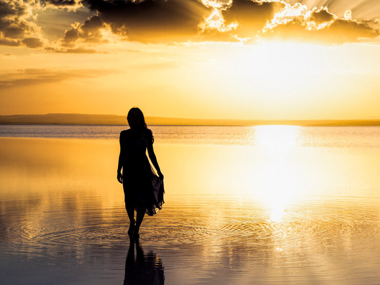 Person vor Gewässer mit Sonnenuntergang führt schamanische Seelengespräche